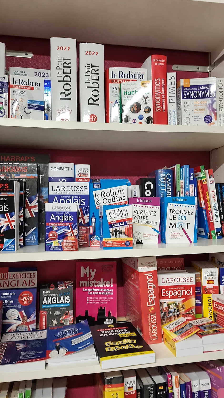 Le rayon des dictionnaires et des méthodes de langues sur des étagères blanches et rouges
