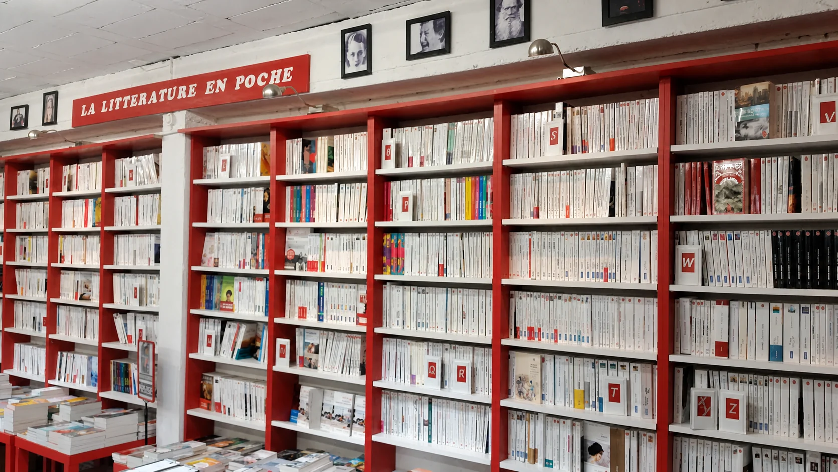 Le long rayon de littérature en poche, classé dans de grandes bibliothèques rouges et blanches